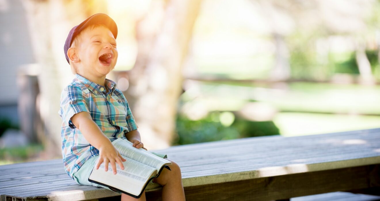 boy sitting on bench while holding a book